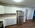 Modern kitchen with sleek white cabinetry, stainless steel fridge, and elegant wood flooring, offering a stylish and functional cooking space.