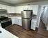 Modern kitchen with sleek stainless steel appliances, crisp white cabinetry, and elegant dark wood flooring.