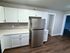 Modern kitchen with sleek white cabinets, stainless steel refrigerator, and stylish tile backsplash.