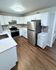 Modern kitchen with sleek stainless steel appliances, elegant white cabinetry, and warm wood flooring.
