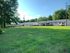 Charming row of apartments surrounded by lush green lawn and mature trees, offering serene and inviting living spaces.