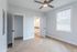 Bright modern bedroom featuring sleek light wood flooring, a large window with blinds, and an elegant ceiling fan, offering a tranquil living space.