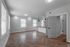 Modern open-concept apartment with elegant herringbone wood flooring, bright natural light from large windows, and a sleek kitchen featuring stylish pendant lighting and contemporary design.