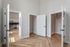 Inviting apartment interior showcasing sleek white doors, elegant light wood flooring, and a modern kitchen with stainless steel appliances.