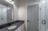 Modern bathroom featuring sleek black countertop, stylish white cabinetry, and elegant glass shower door.