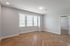 Bright and inviting room with elegant herringbone wood flooring, large triple windows, and modern lighting.
