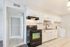 Modern kitchen with sleek black appliances, white cabinetry, and elegant tile backsplash, adjacent to a compact laundry area.