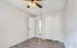 Bright and airy bedroom with elegant wood flooring, sleek ceiling fan, and spacious built-in closet.