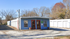 Charming blue office building with red doors and spacious outdoor storage units, set against a backdrop of autumn trees.