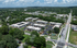 Vibrant aerial view of a modern apartment complex, surrounded by lush greenery and well-connected roads, showcasing community living at its finest.