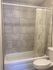 Charming bathroom featuring elegant stone tile walls, a cozy bathtub with a nature-inspired shower curtain, and a sleek white toilet.
