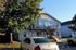 Charming two-story apartment building with modern exterior and expansive balconies nestled among lush greenery, offering convenient parking and serene living.