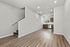 Contemporary open-plan living space featuring elegant hardwood floors, an inviting staircase, and a modern kitchen with sleek cabinetry and stainless steel appliances.