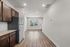 Modern open-concept apartment showcasing chic hardwood floors, a stylish kitchen with dark wood cabinets and stainless steel appliances, leading to a bright living area with large windows.