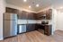 Modern kitchen with sleek stainless steel appliances, dark wood cabinetry, and elegant hardwood flooring.