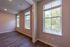 Bright and inviting room with large windows letting in natural light, enhancing the appeal of the wood flooring.