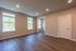 Bright, spacious room with elegant wood flooring, large windows, and modern recessed lighting.
