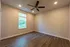 Inviting room with elegant wood flooring, fresh beige walls, and a sleek ceiling fan creating a cozy ambiance.