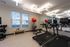 Modern fitness room featuring state-of-the-art treadmills, free weights, and exercise balls with ample natural light and contemporary lighting.