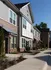 Charming modern townhouse exterior with large windows, landscaped walkway, and inviting entryways under a clear blue sky.