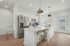 Chic modern kitchen with high-end stainless steel appliances, white cabinetry, and a stylish breakfast bar with elegant lighting.
