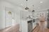 Chic open-plan kitchen with sleek island, pendant lighting, and inviting living room boasting large windows and cozy seating.