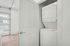 Bright laundry area featuring a stacked washer and dryer with modern design, conveniently located in a sleek apartment interior with wood flooring.
