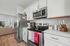 Modern kitchen with stainless steel appliances, sleek white cabinets, and cozy view into inviting living room.