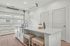 Bright, modern kitchen with white cabinetry and a spacious island, featuring garage-style windows for ample natural light.
