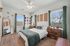 Bright and cozy bedroom with stylish decor, large windows, and a chic wooden floor for an inviting ambiance.