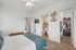 Bright and inviting bedroom with modern ceiling fan, featuring a cozy bed adorned with a teal blanket. Adjacent walk-in closet offers ample storage, while the ensuite bathroom adds convenience. Stylish flooring completes this comfortable space.