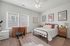 Bright and airy bedroom featuring a cozy bed, stylish decor, a chic wooden desk, and large windows letting in natural light.