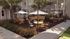 Charming courtyard with cozy seating areas under elegant umbrellas, surrounded by lush greenery and decorative string lights for a perfect outdoor gathering.