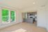 Bright and airy living space with large windows and a modern kitchen featuring sleek grey cabinets and stainless steel appliances.