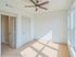 Bright and inviting empty room with modern ceiling fan, large windows, and ample natural light enhancing the minimalist design.