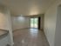 Bright living area with tile flooring and a large sliding glass door overlooking lush greenery.