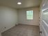 Bright, inviting room with tiled flooring and natural light from a large window, ideal for versatile living.