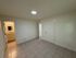 Bright, minimalist room with tiled floor, featuring access to a modern bathroom and ample storage space.
