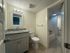 Modern bathroom with elegant granite countertop, bright lighting, and sleek tile flooring.