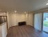 Bright and inviting living room with sleek hardwood floors, modern lighting, and a view of the lush outdoor landscape through sliding glass doors.