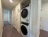 Modern hallway featuring elegant hardwood floors and a convenient in-unit washer and dryer set.