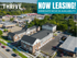 Vibrant aerial view of Thrive apartment complex showcasing modern architecture, lush surroundings, and ample parking. Now leasing with immediate move-in availability, offering a thriving community lifestyle.