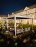 Inviting community outdoor space at night featuring comfortable seating and modern pergolas, surrounded by charming townhouses.