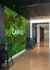 Modern lobby featuring a vibrant green vertical garden, sleek black high tables and chairs, and an inviting hallway accented with natural light and contemporary design.