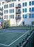 Modern apartment building with private balconies overlooking a well-maintained tennis court, promoting an active lifestyle.