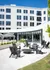 Modern outdoor patio with comfortable seating, a sleek fire pit, and a contemporary glass-fronted building backdrop, perfect for relaxing and socializing.