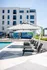 Modern apartment complex with a stunning pool area, featuring sleek lounge chairs and artistic mural backdrop.