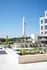 Luxurious apartment complex boasting a beautiful outdoor pool area with stylish loungers and chic umbrellas, surrounded by lush greenery and modern architecture under a clear blue sky.