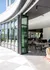 Bright and modern office space with sleek glass doors opening to a sunlit patio, providing an ideal blend of indoor and outdoor work environments.