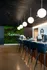 Chic modern bar area with sleek black chairs, illuminated by stylish globe lights, set against a vibrant green wall with the name Canvas.